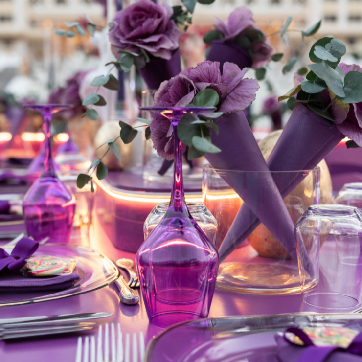Dusty mauve wedding table setting with mauve wine glasses, roses and eucalyptus decorations and mauve table cloth.
