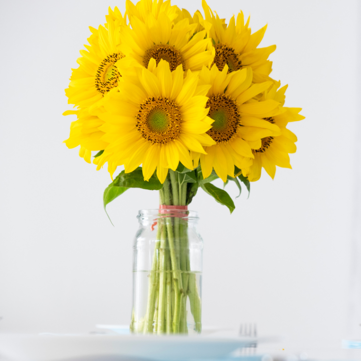 Bride to bee bridal shower table decoration of a bunch of sunflowers in a clear glass jar.