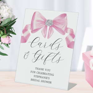 Shes tying the knot bridal shower coquette themed cards and gifts pedestal sign featuring a chic glam silky pink bow with sparkling rhinestones design and modern script typography.