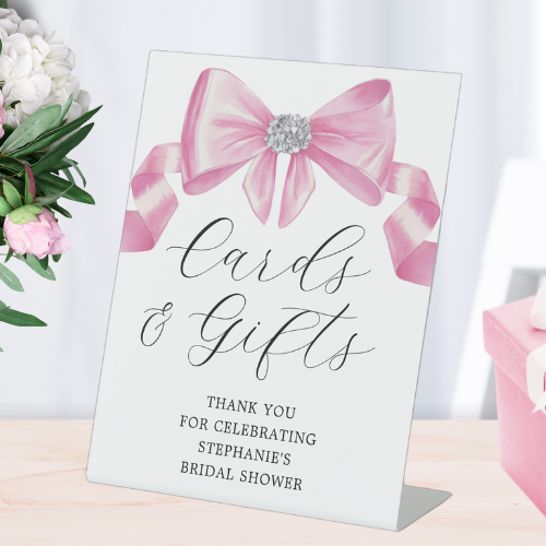 Shes tying the knot bridal shower coquette themed cards and gifts pedestal sign featuring a chic glam silky pink bow with sparkling rhinestones design and modern script typography.